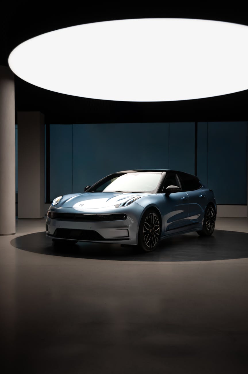 A futuristic blue car showcased under stylish lighting in a modern showroom.